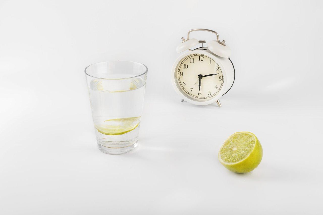 Un verre d’eau tiède citronnée au réveil, posé sur une table de chevet pour bien commencer la journée.