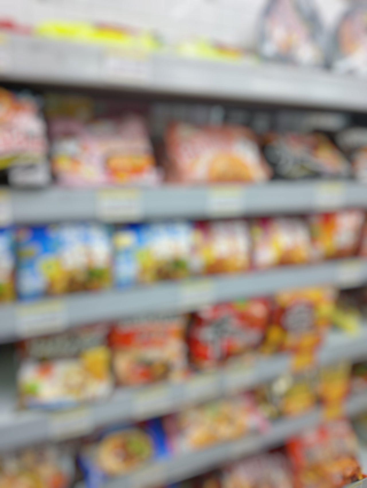 Un contraste marqué entre aliments ultratransformés en emballages colorés et ingrédients bruts sur un comptoir.