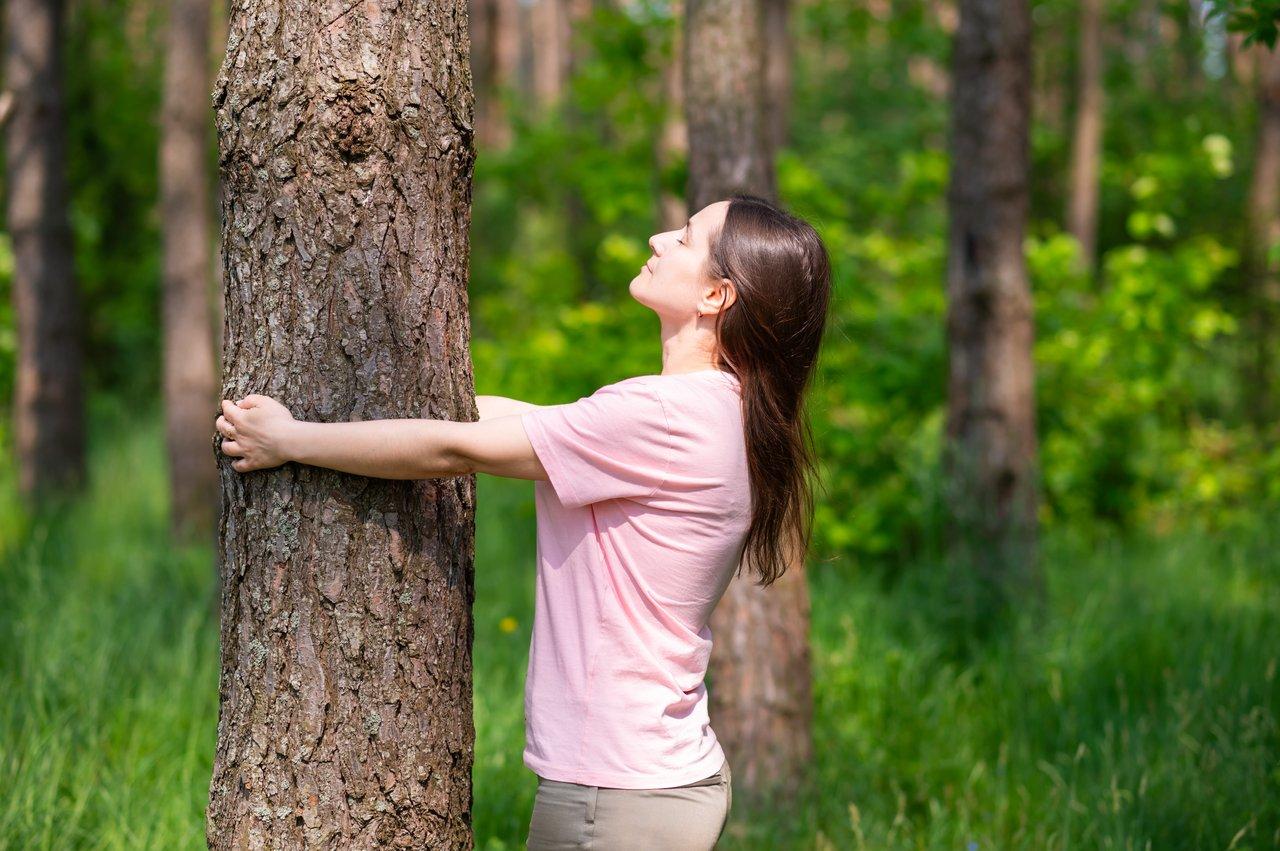 Illustration de la connexion entre corps, esprit et nature, symbolisée par une femme en harmonie avec un grand arbre.