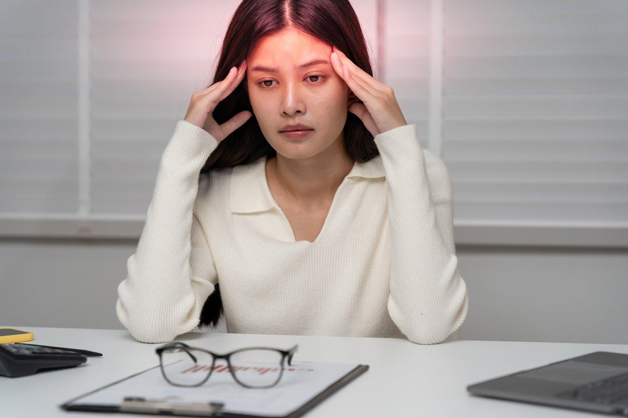 Une femme souffre d'une migraine dans une dark room pour soulager la douleur et éviter les stimuli.